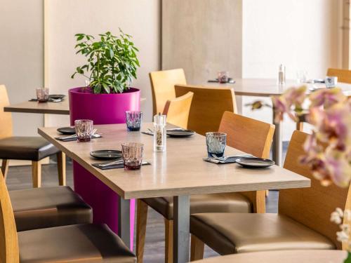 a table with plates and glasses on it in a restaurant at Mercure Strasbourg Aéroport in Ostwald
