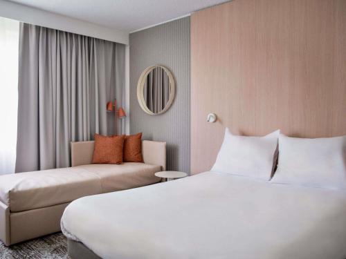 a hotel room with a bed and a couch at Novotel Bordeaux Mérignac in Mérignac