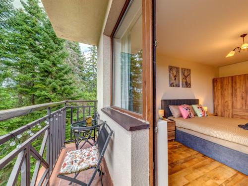 a balcony of a house with a bed and a window at Apartment Kapina in Pamporovo