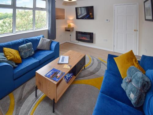 a living room with blue couches and a coffee table at Station House in St Bees