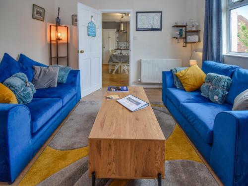 a living room with blue couches and a coffee table at Station House in St Bees