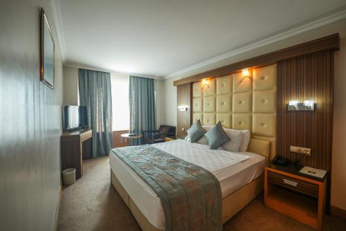 a hotel room with a bed and a television at Surmeli Adana Hotel in Adana