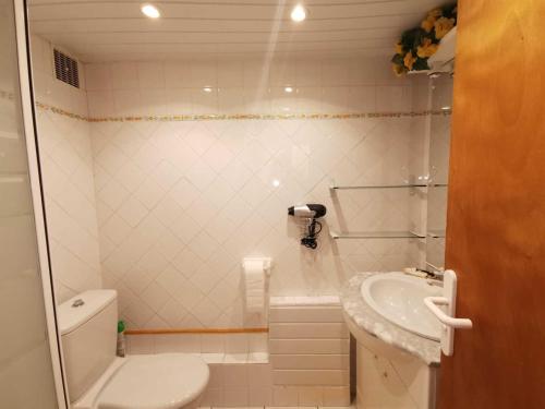 a white bathroom with a sink and a toilet at Les lauriers in Sahorre