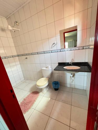 a bathroom with a toilet and a sink and a mirror at Pousada Marialva in Barreiras