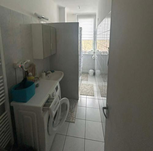 a small kitchen with a sink and a washing machine at Digitális Detox Apartman in Tiszafüred