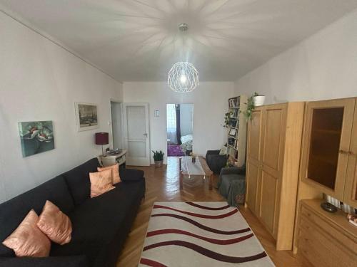 a living room with a couch and a chandelier at Digitális Detox Apartman in Tiszafüred