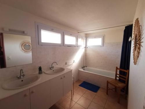 a bathroom with two sinks and a tub and two windows at Rouvenac in Trilla