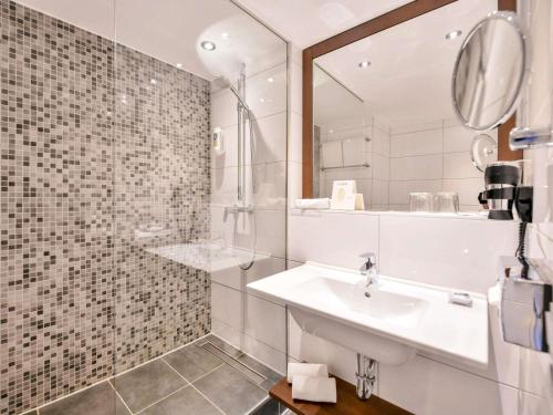 a white bathroom with a sink and a mirror at Mercure Aachen Europaplatz in Aachen