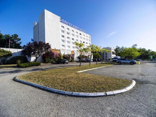 a large building with a circle in a parking lot at Mercure Bordeaux Lac in Bordeaux