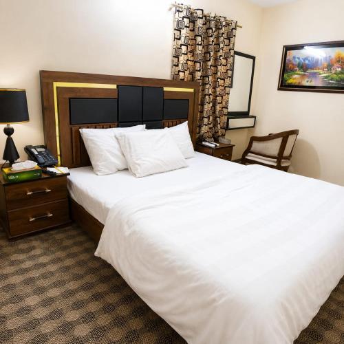a bedroom with a large white bed and a telephone at HillTop Hotel in Karachi