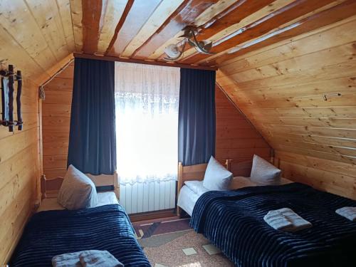 two beds in a wooden room with a window at День і ніч in Slavske