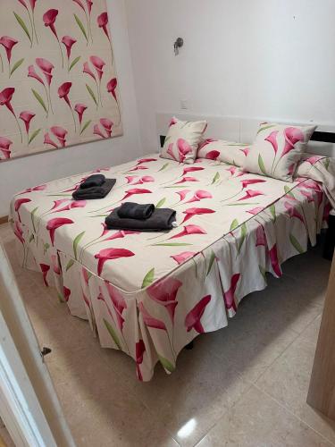 a bed with pink flowers on it in a bedroom at Chalet Calan Bosch in Cala en Bosc