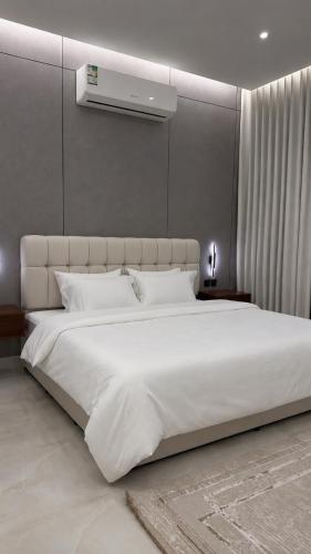 a bedroom with a large white bed and a wall at شقة بغرفتين نوم وصالة in Hail