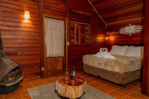 a bedroom with a bed and a table with wine glasses at Pousada Olivier da Montanha in Santo Antônio do Pinhal