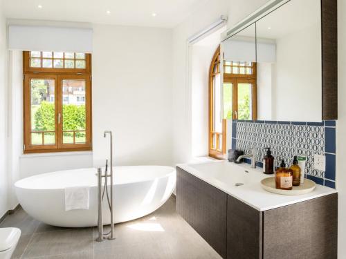 a white bathroom with a tub and a sink at Villa Flora 1909 - Private Alpine Residence in Grindelwald