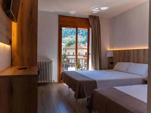 a hotel room with two beds and a window at El 9 Baral-la in Sant Pau de Segúries