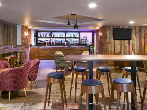 a bar with a wooden table and chairs and a bar at Novotel Manchester West in Worsley