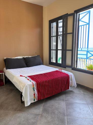 a bedroom with a bed with a red blanket on it at Maison Sevilla in Larache
