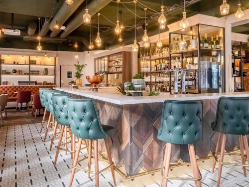 a bar with blue bar stools in a restaurant at Mercure Paris Bercy Bibliothèque in Paris
