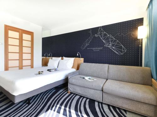 a hotel room with a bed and a couch at Novotel La Rochelle Centre in La Rochelle