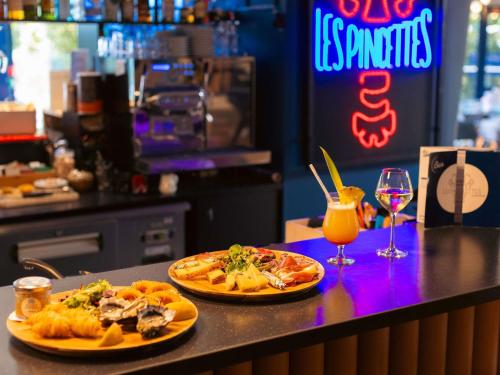 two plates of food on a counter with a drink at Novotel La Rochelle Centre in La Rochelle
