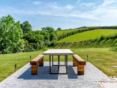 a picnic table and two benches in a field at The Black Barn in Marldon