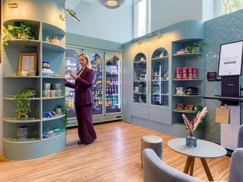 a woman is standing in a store aisle at Mercure Hotel Hannover City in Hannover