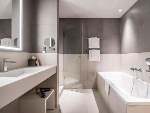 a bathroom with two sinks and a tub and a shower at Novotel Brugge Centrum in Bruges