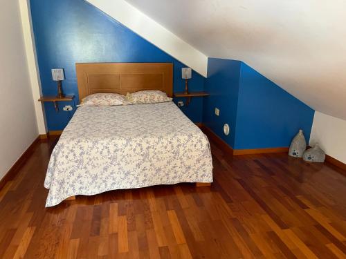 a bedroom with a bed with blue walls and wooden floors at Yellow Attic in Senhora do Rosário