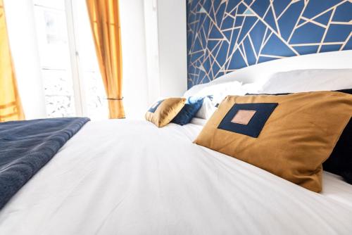 a white bed with two pillows on top of it at MM Suites Marlot in Reims