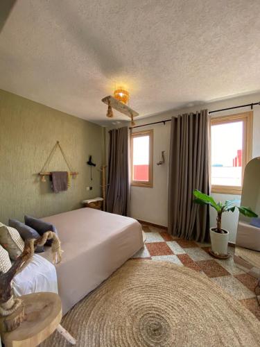 a bedroom with a large white bed and a rug at The FlowHost in Tamraght Ouzdar