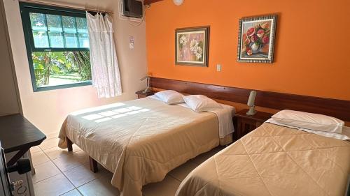 two beds in a room with orange walls at Pousada Villa Harmonia in Paraty
