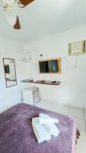 a bedroom with a purple bed with two white towels at Bella vida Geriba suites in Búzios