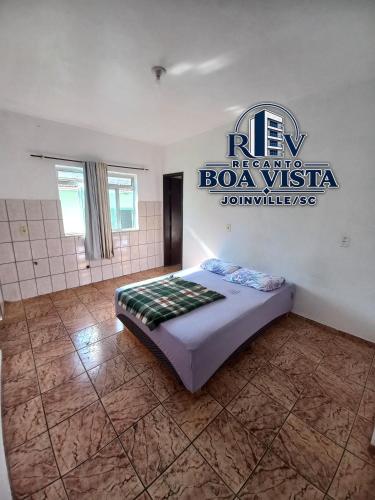 a bedroom with a bed with a sign on the wall at Recanto Boa Vista in Joinville