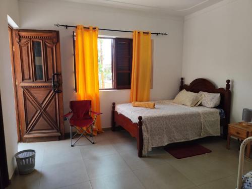a bedroom with a bed and a door and a chair at Barros Homestay in Tarrafal