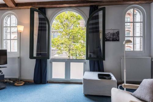 a living room with two large windows and a chair at Anny's Warehouse City Centre! in Amsterdam