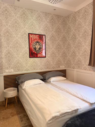 a bed in a bedroom with a poster on the wall at Le Clocher de la Duchesse in Bonnelles