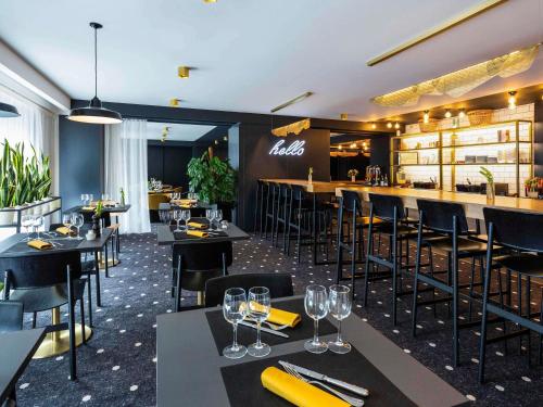 a restaurant with black tables and chairs and a bar at Mercure Bordeaux Centre Ville in Bordeaux