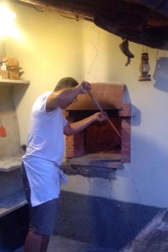 a man is putting something into a brick oven at Agriturismo Tripala in Minucciano