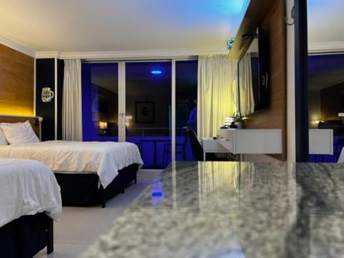 a hotel room with two beds and a glass table at Ocean Manor Tiki Sunset Retreat in Fort Lauderdale
