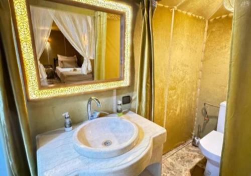 a bathroom with a sink and a mirror and a toilet at Sahara Legacy Camp in Merzouga
