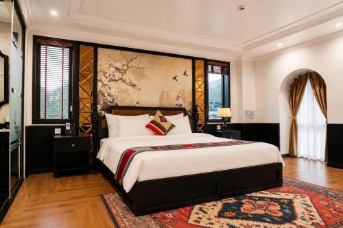 a bedroom with a large bed and a painting on the wall at Anara Sapa Hotel & Coffee in Sapa
