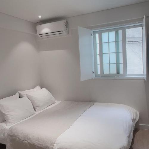 a white bedroom with a bed and a window at Staymoment in Seoul