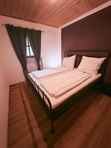 a bed with white sheets and pillows in a room at Ferienwohnung WAUzenberg mit Pool und Sauna in Hauzenberg