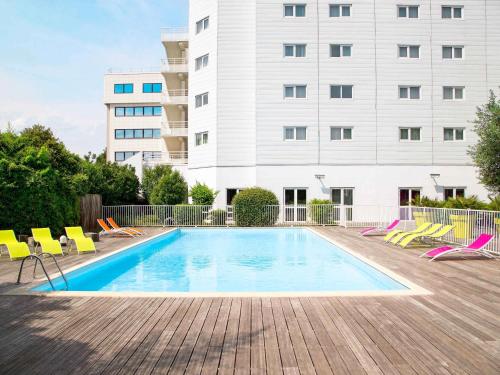 a swimming pool with chairs and a building at Novotel Paris Orly Rungis Aéroport in Rungis
