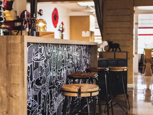 a bar with stools in front of a counter at ibis Saint Brieuc Yffiniac in Yffiniac