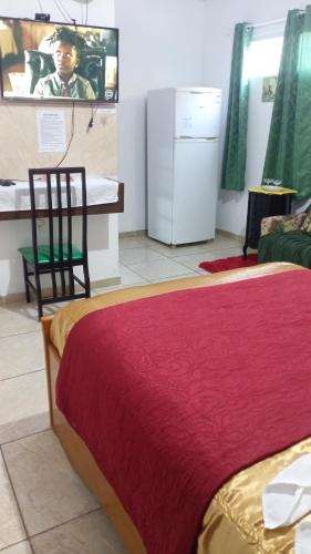 a bedroom with a bed with a red blanket and a chair at Suites in Domingos Martins