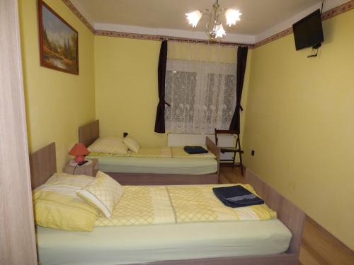 two beds in a room with yellow walls at Kovács Vendégház in Zalaegerszeg