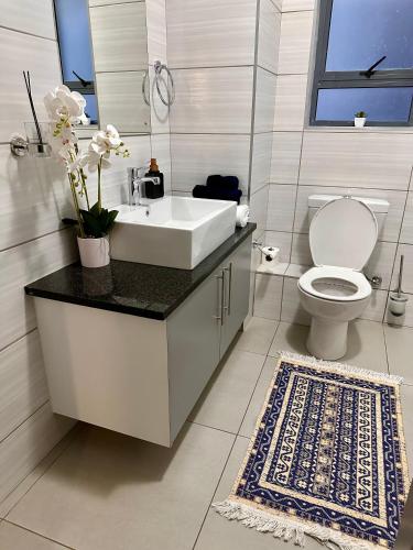 a white bathroom with a sink and a toilet at Nova Apartments- MbabaneCBD in Mbabane