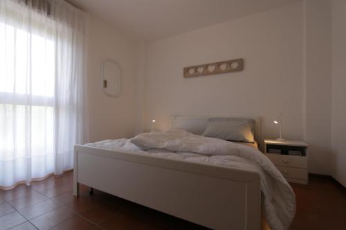 a white bedroom with a bed and a window at Reunia apartments in Ragogna